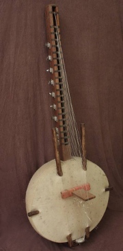 Na zdjęciu instrument muzyczny - kora. Pół kuli z naciągniętą membraną ze skóry i z długim kijem z zamontowanymi strunami